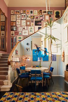 a dining room table with blue chairs and pictures on the wall in front of it