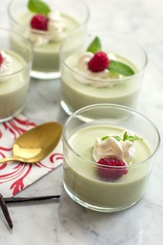 three desserts in small glass bowls with raspberries and whipped cream on top