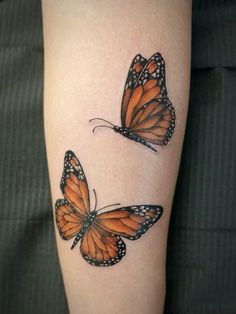 two orange butterflies on the left arm, one with black spots and one with white dots