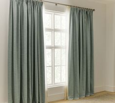 the curtains are closed in front of a window with white walls and wood flooring