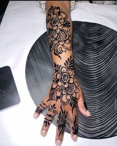 a woman's hand with henna tattoos on it and her hands in the shape of flowers