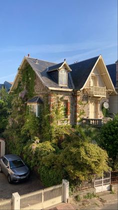 a car is parked in front of a house with vines growing on the side of it