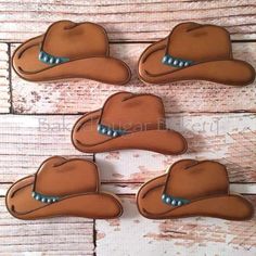 four cowboy hats decorated cookies sitting on top of a wooden table