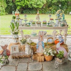 a table with many items on it in the middle of a yard, surrounded by grass and flowers