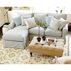 a living room with a couch, ottoman and coffee table in front of a window