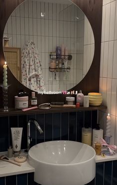 a white sink sitting under a round mirror in a bathroom next to a counter top