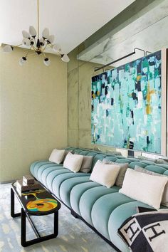 a living room filled with lots of blue couches next to a painting on the wall