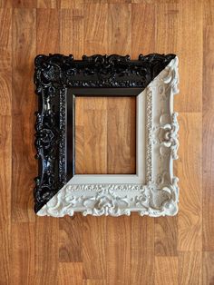 an old black and white frame sitting on top of a wooden floor