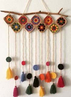 a group of tassels hanging from a wooden stick on a wall with other tassels attached to it