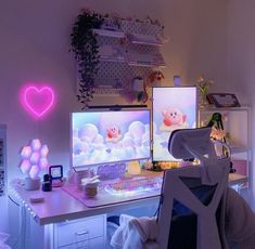 a computer desk with two monitors on it and a heart shaped neon sign above the monitor