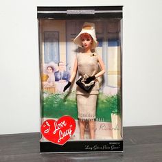 a barbie doll in a plastic box with a heart on the front and an image of a woman holding a purse