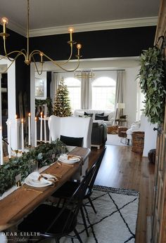 the dining room table is set for christmas with candles and greenery on it's side