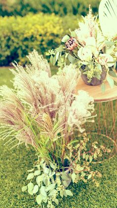 flowers and plants are sitting on a small table in the middle of some green grass