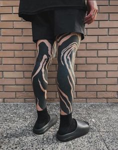 a person with black and white patterned leggings standing in front of a brick wall