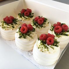 there are many small cakes with raspberries on them in a white box together