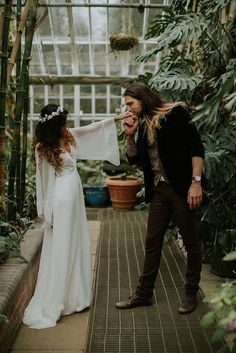 a man and woman standing next to each other in a greenhouse