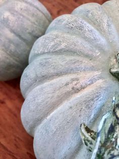 two white pumpkins sitting on top of a wooden table