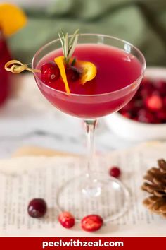 cranberry martini with orange peel garnish in a coupe glass on top of an open book