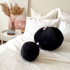 two black pillows sitting on top of a white bed