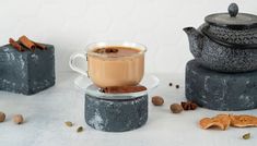 a cup of coffee sitting on top of a glass saucer next to some nuts