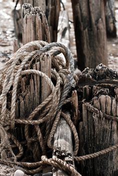 an old wooden post with ropes and rope on it's end in the sand