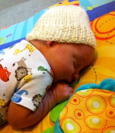 a baby sleeping on top of a blanket wearing a knitted hat and diaper