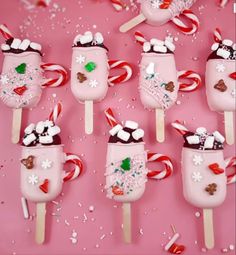 candy canes and marshmallows are arranged on a pink surface