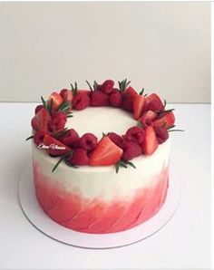 a cake decorated with strawberries on top of a white plate and topped with greenery