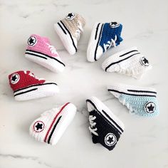 six crocheted converse sneakers arranged in a circle on a marble surface with white and black accents