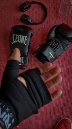 a person wearing boxing gloves next to other items on a red carpeted surface with one hand in the air