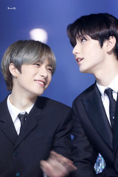 two young men in suits are smiling at each other