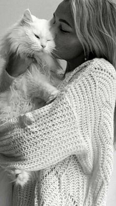 a woman holding a white cat in her arms