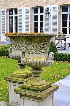 a large urn sitting on top of a cement block in front of a building