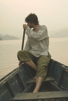 a man sitting in the back of a boat on top of water with his hands to his face