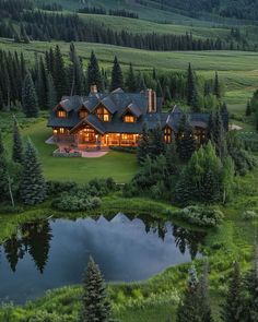 an aerial view of a large home surrounded by trees and water in the evening light