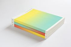 three colored notebooks stacked on top of each other with the same color paper in front of them