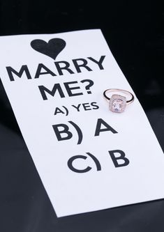 a sign that says marry me? with a diamond ring on it's side