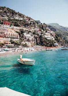 a boat floating on top of a body of water next to a hillside covered with houses