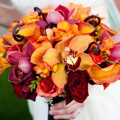 a bride holding a bouquet of orange and red flowers