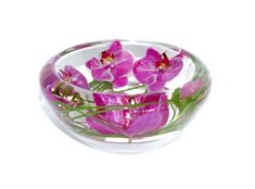 a glass bowl filled with pink flowers on top of a white table