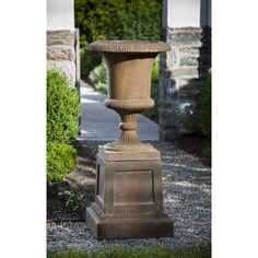 a stone urn sitting in the middle of a garden