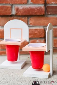 two plastic cups sitting on top of each other next to a basketball hoop and an orange ball