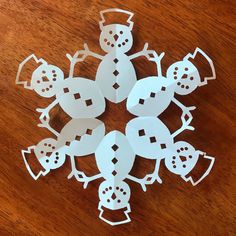 paper cut snowmen sitting on top of a wooden table