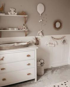 a baby's room with a crib, dresser and teddy bear decorations on the wall