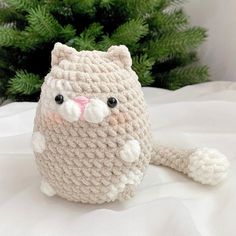 a crocheted cat sitting on top of a bed next to a christmas tree