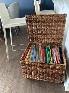 a wicker storage basket filled with colored pencils on the floor next to a dining room table