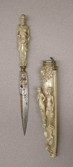 two ivory figurines are next to each other on a gray surface with a knife in the foreground