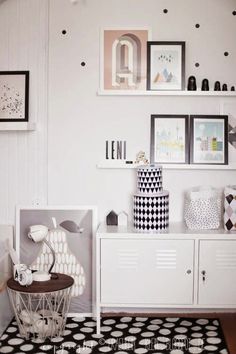 a black and white room with polka dots on the walls, furniture and pictures above it