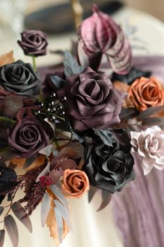 an arrangement of flowers in a vase on top of a table with purple and orange colors