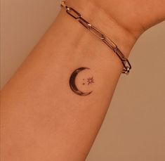 a woman's wrist with a small crescent tattoo on the left side of her arm